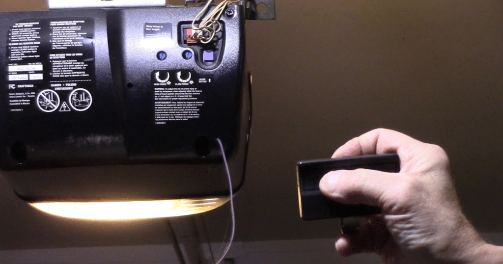 Hand holds remote near Craftsman garage opener unit